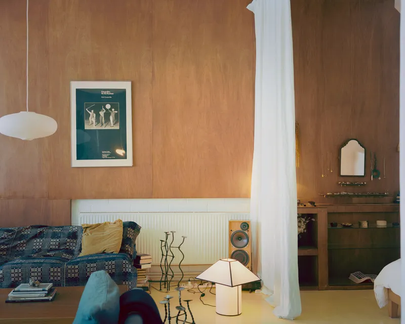 Sleeping alcove with plywood wall paneling and white column wrapped in sheer fabric