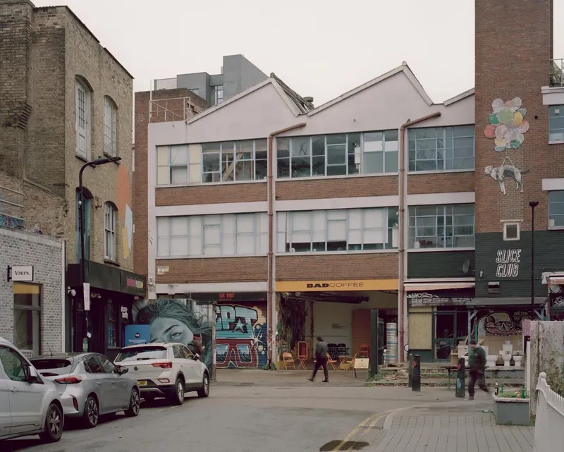 Street view of mixed-use building facades with exposed brick and storefronts with graffiti