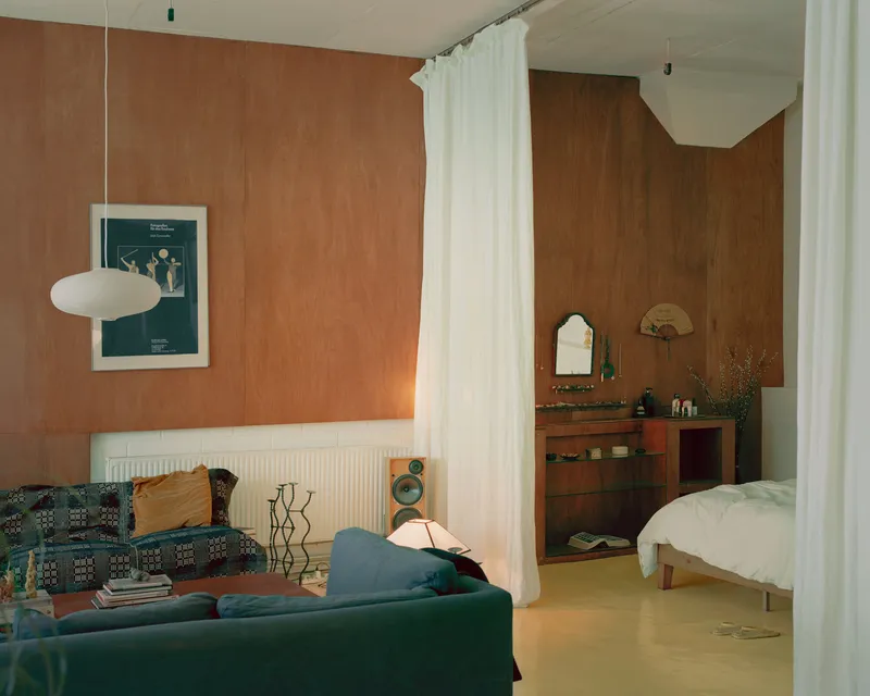 Living area with terracotta fabric wall panels and white curtain divider on yellow flooring
