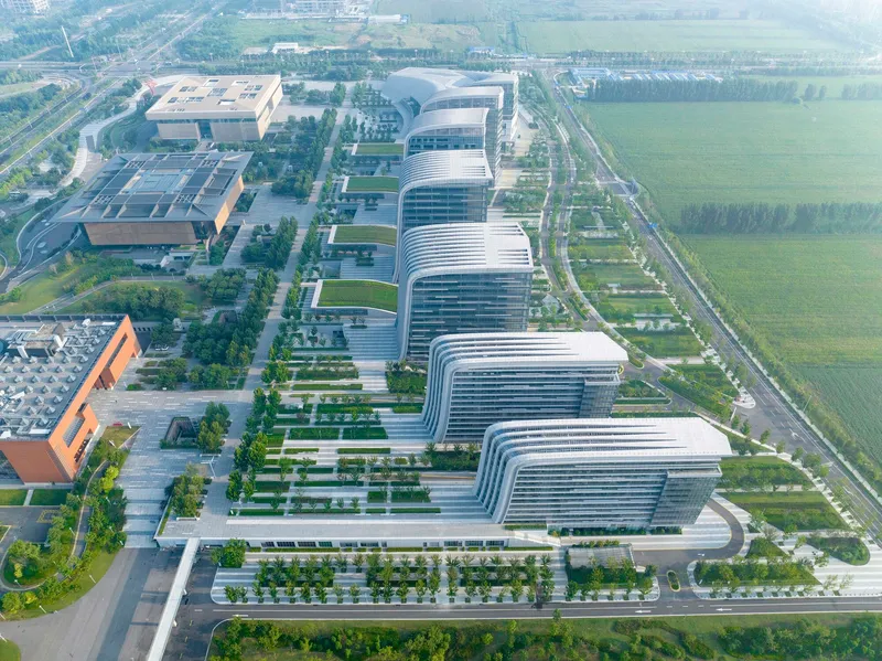 Aerial perspective showing the repeating ribbed facade rhythm of office towers along tree-lined streets