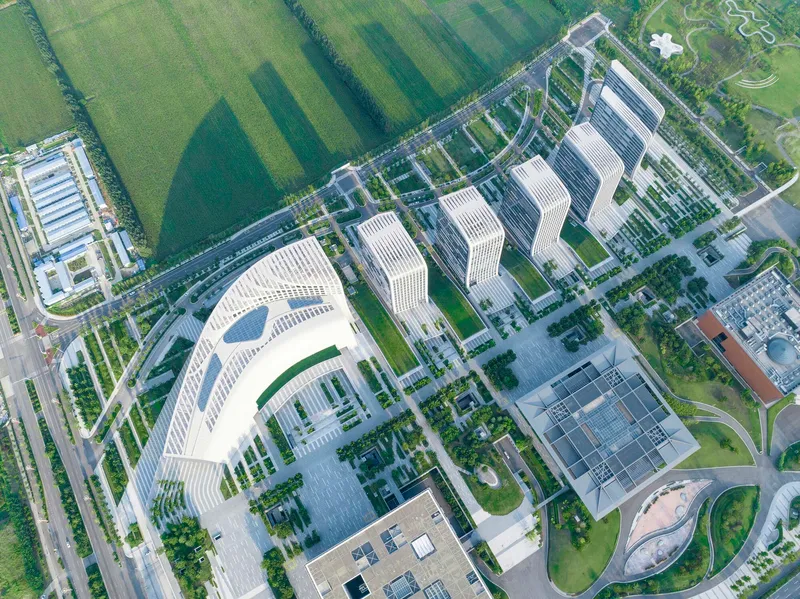 Overhead view of a crescent-shaped tower with horizontal banding beside rectangular blocks and courtyards