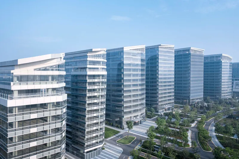 Horizontal banded glass facades of multiple towers above a landscaped courtyard with curved pathways