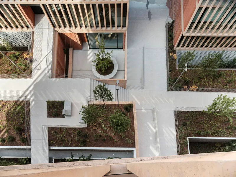 Aerial view of terraced rooftop gardens with timber screens and circular planters in morning sunlight