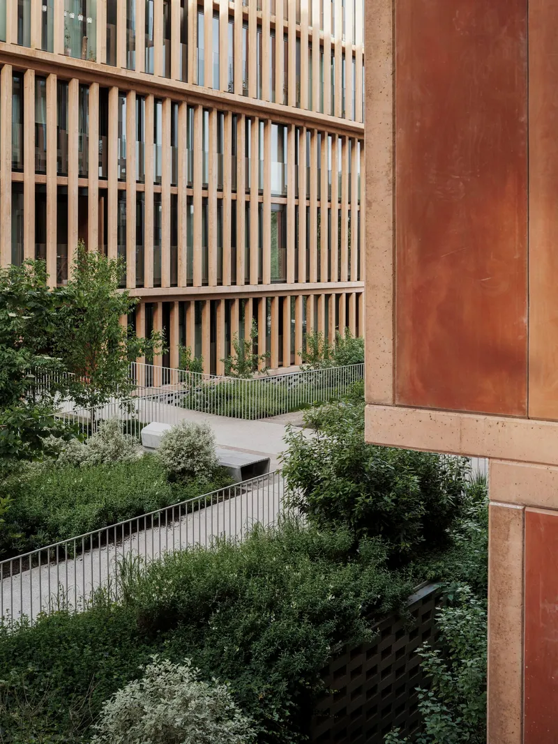 Terraced planted balconies with metal railings between timber screened facades and weathered steel panels