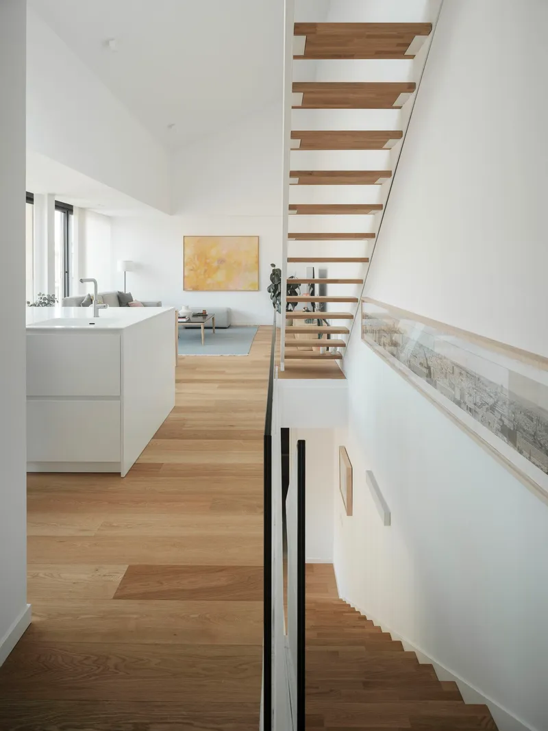 Open-tread timber staircase connecting two levels with white walls and light oak flooring