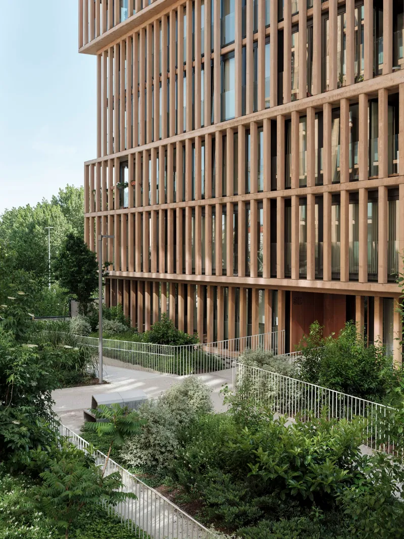 Curving pathway with metal railings and planted beds beneath the timber-louvered tower facade