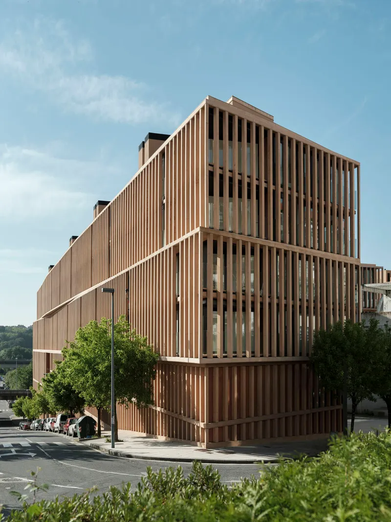 Corner view of the vertical timber screen facade under a blue sky with scattered clouds