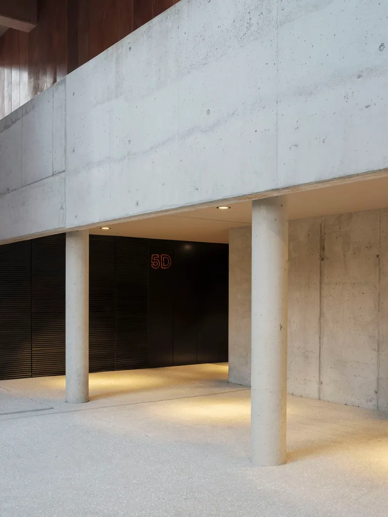Concrete lobby with cylindrical columns and strip lighting beneath the ceiling soffit