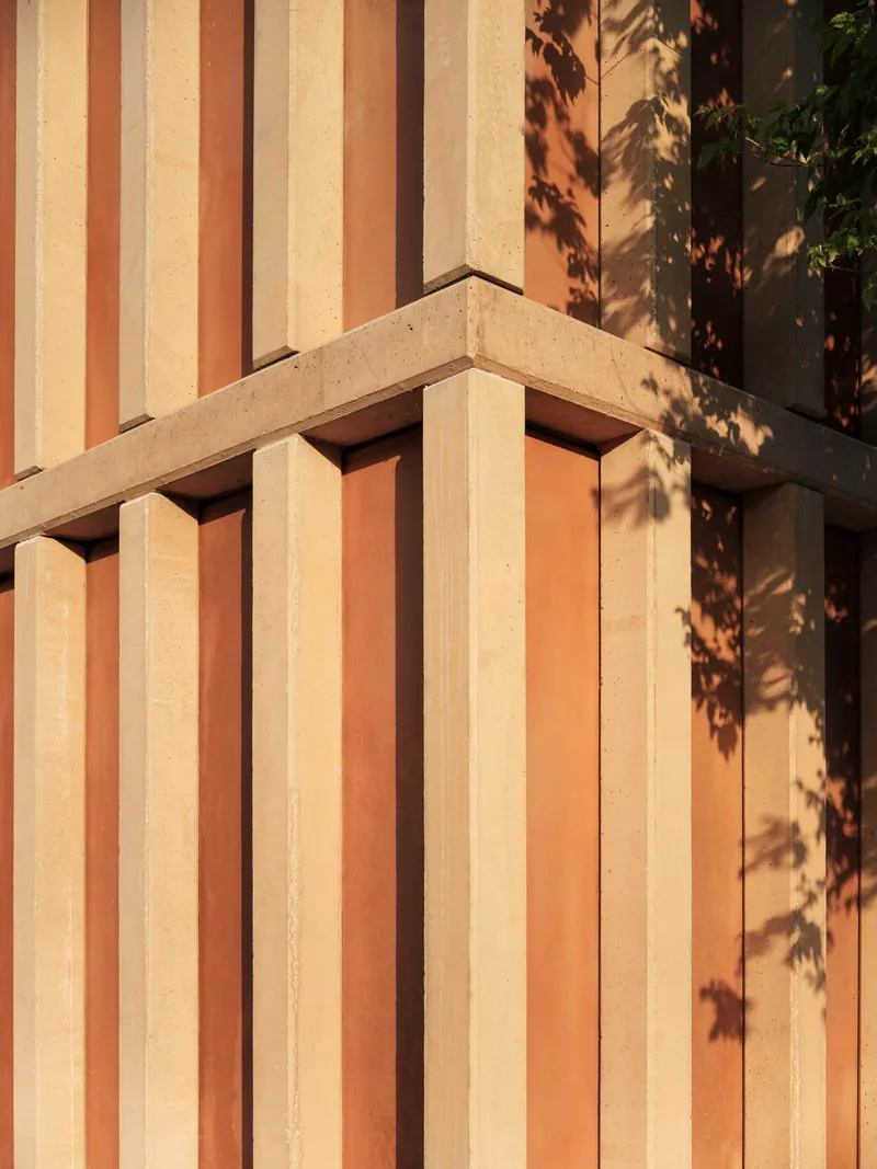 Close-up of vertical timber slat cladding junction with concrete beam edge casting dappled shadow