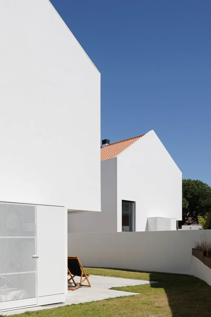 White rendered volumes with terracotta tile roof and curved garden wall beneath blue sky