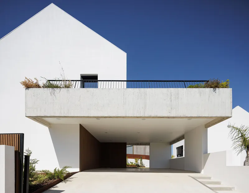 Cantilevered concrete terrace with integrated planter above a recessed entry carport in bright midday sun