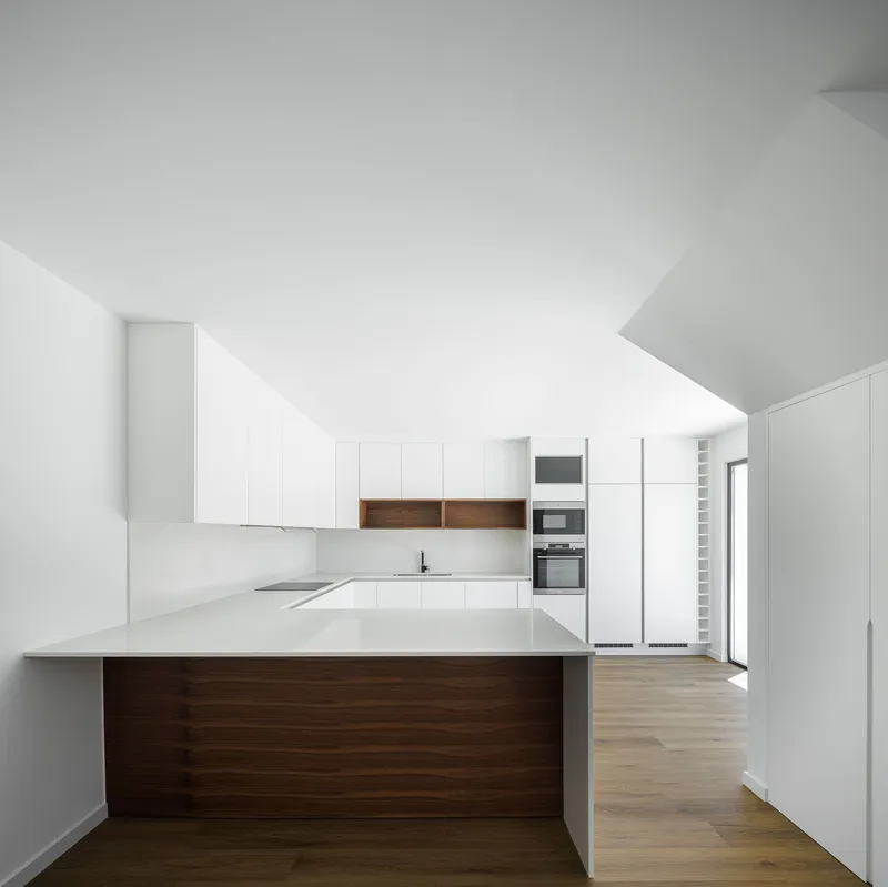 Kitchen with white cabinetry, walnut timber island, and light oak flooring under sloped ceiling
