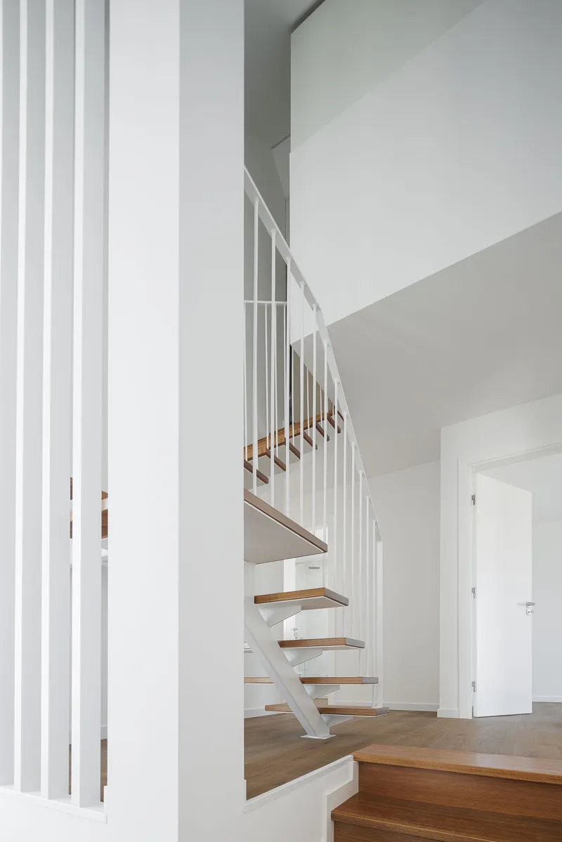 Upper landing view of steel and timber staircase with white vertical screen beside doorway
