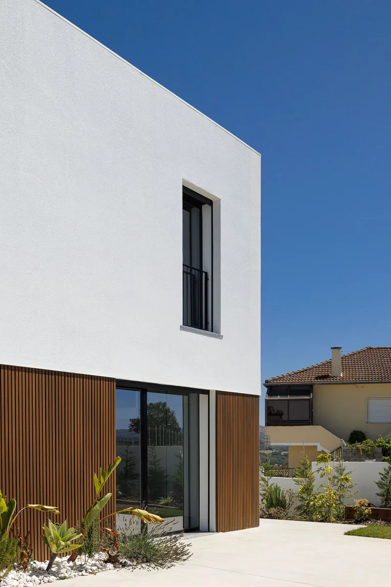 White rendered facade with vertical timber cladding at ground level and narrow window above