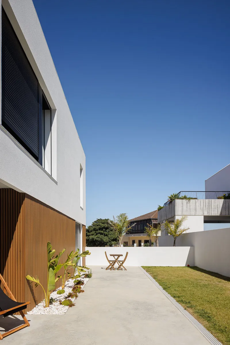 Concrete patio terrace with white perimeter walls, lawn and folding chair in daylight