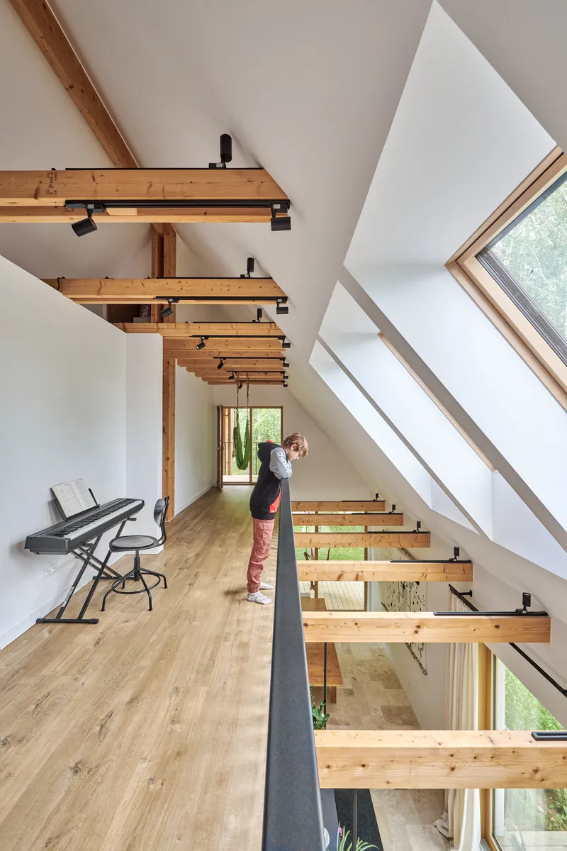 Upper level with exposed timber floor joists and skylight windows framing a person standing in the loft space