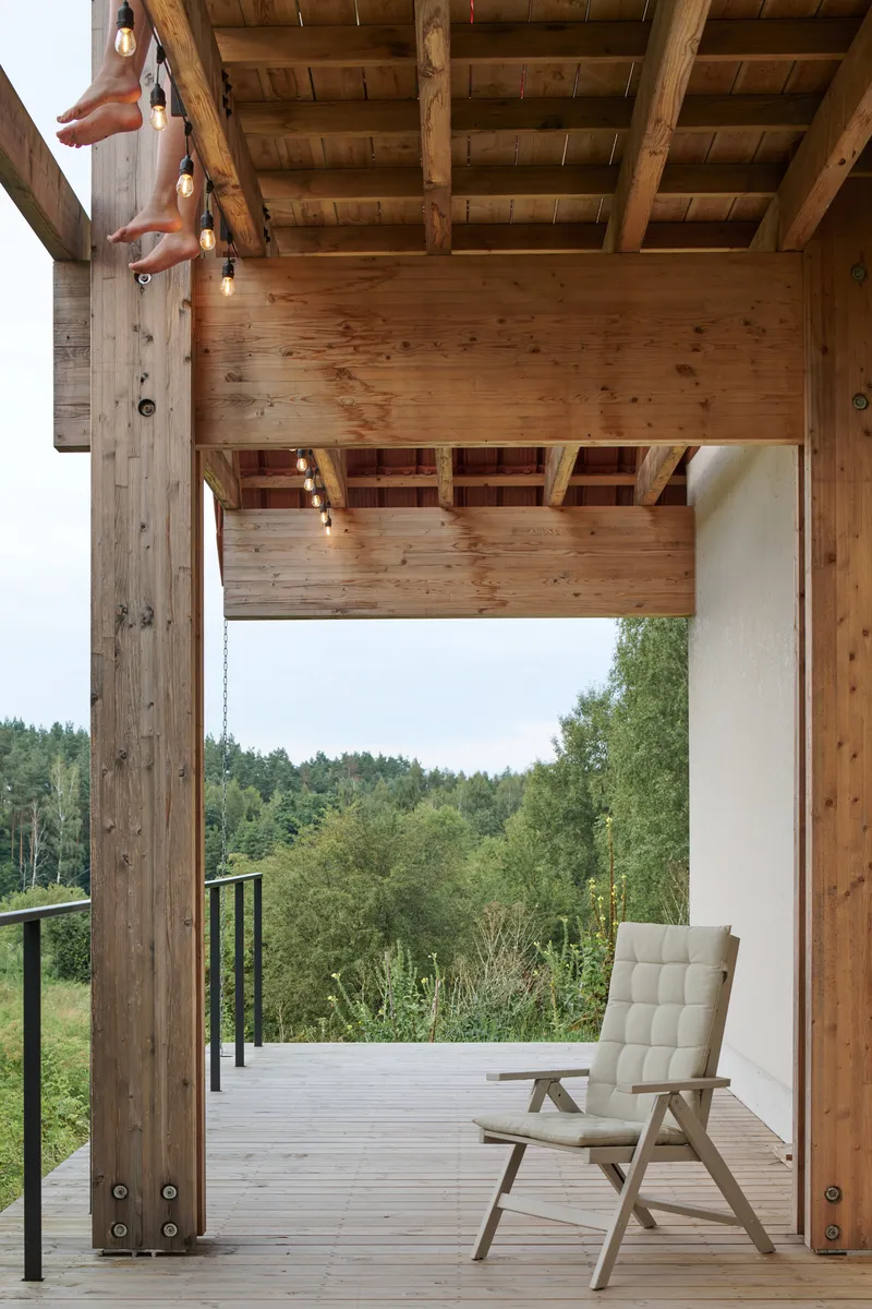 Covered terrace with heavy timber columns and exposed ceiling joists framing distant forested hills