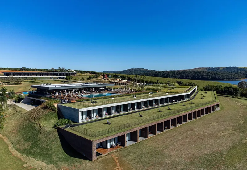 Aerial view of two parallel green roofs stepping down a hillside near a distant lake