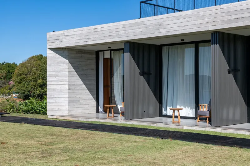 Corner detail showing white horizontal stone cladding meeting dark corrugated wall panels with a recessed terrace opening