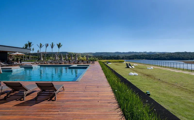 Timber boardwalk extending between pool deck and manicured lawn edge with reservoir view beyond
