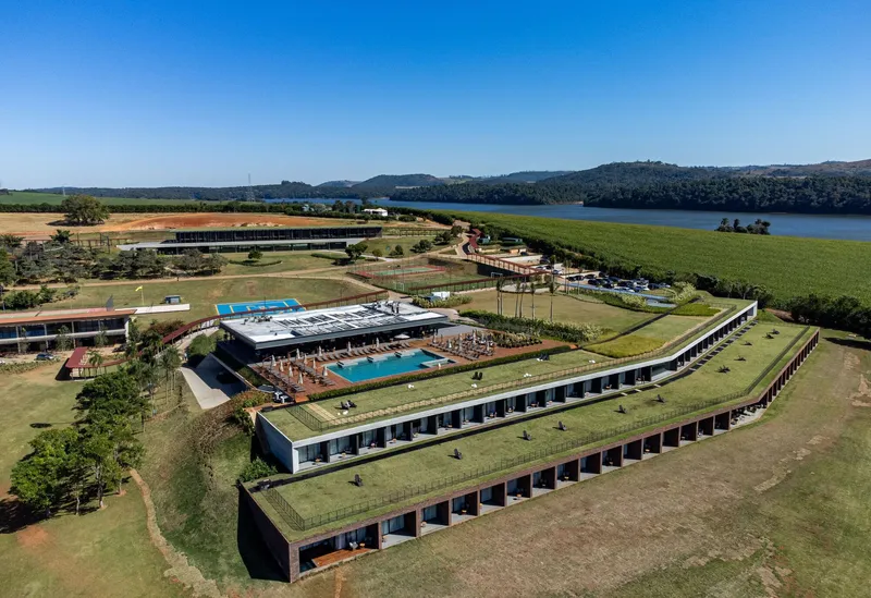 Drone perspective showing the angled green roofs and poolside terrace overlooking agricultural fields