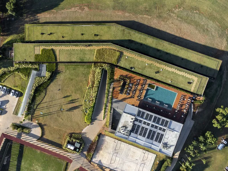 Top-down view of the central pool deck and timber terrace surrounded by planted green roofs
