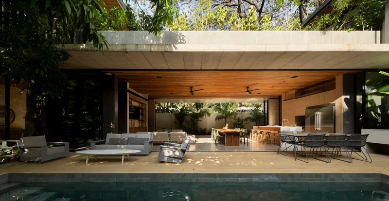 Open terrace with timber ceiling and concrete roof slab overlooking pool and seating area