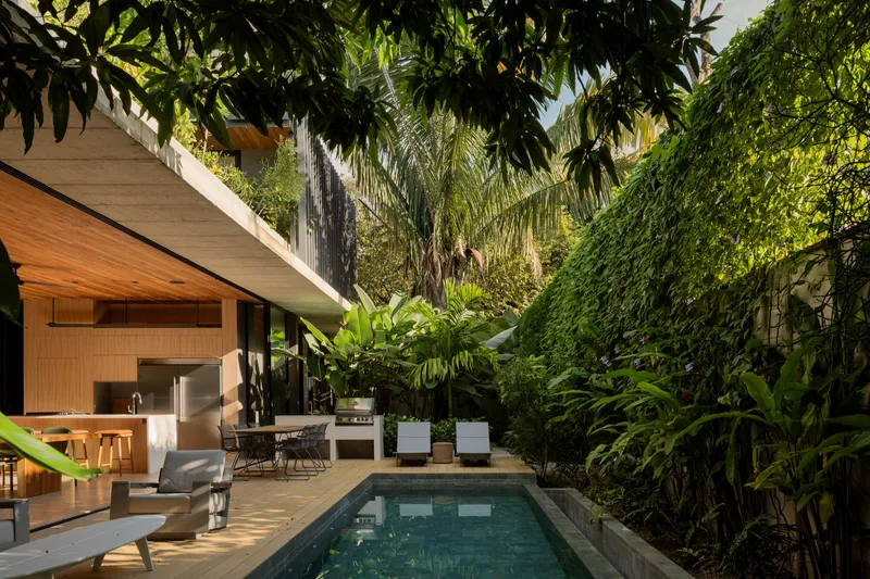 Pool terrace surrounded by dense tropical planting and overhanging concrete roof structure