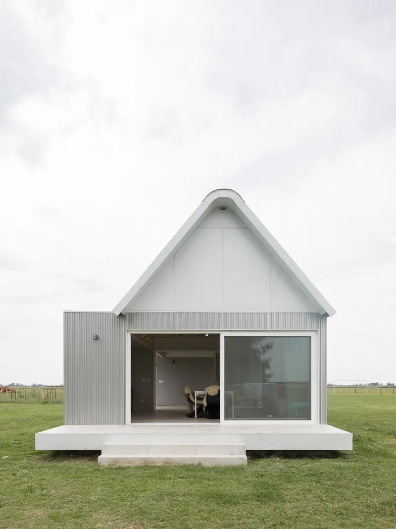 Gable end elevation with corrugated cladding, large glazed opening and concrete platform base