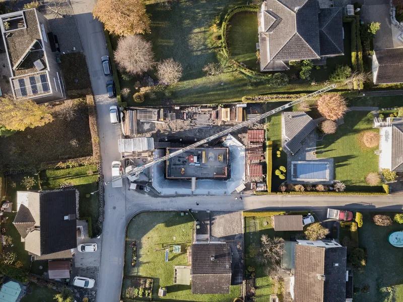 Aerial view of construction site surrounded by residential houses and bare winter trees