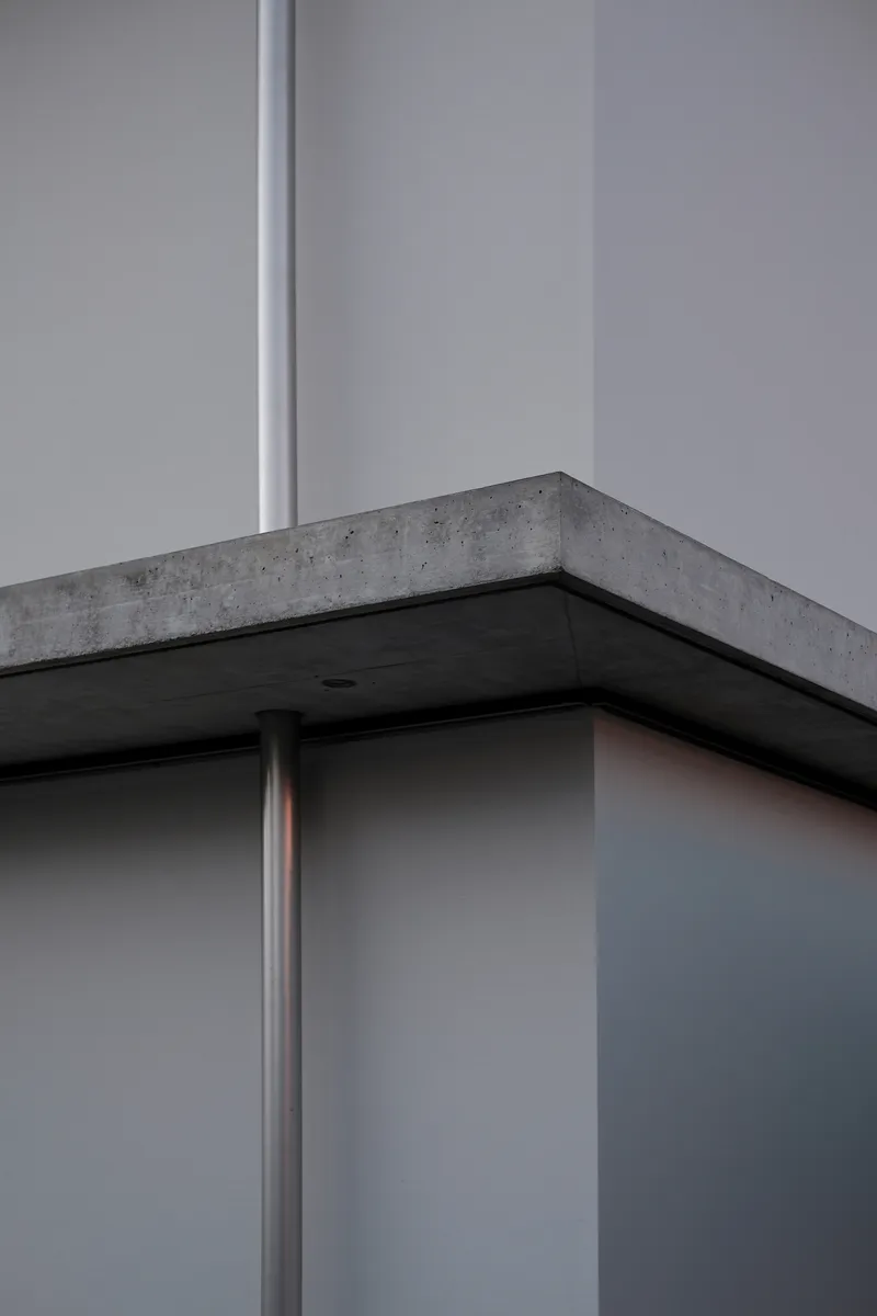 Close-up of concrete beam corner supported by steel column with recessed black soffit panel