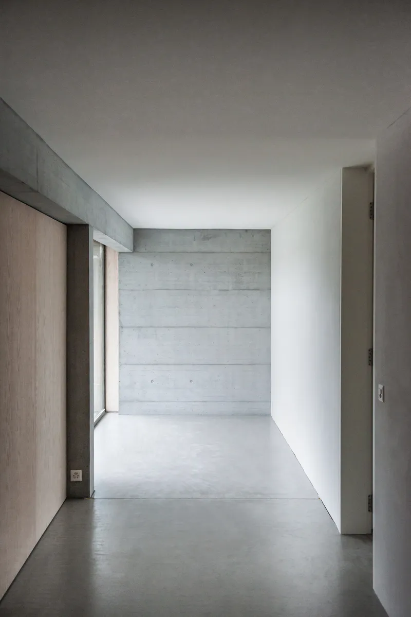 Interior corridor with board-formed concrete end wall and light oak wood panels along one side
