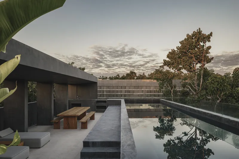 Rooftop terrace with reflecting pool and timber bench under a cloudy dusk sky