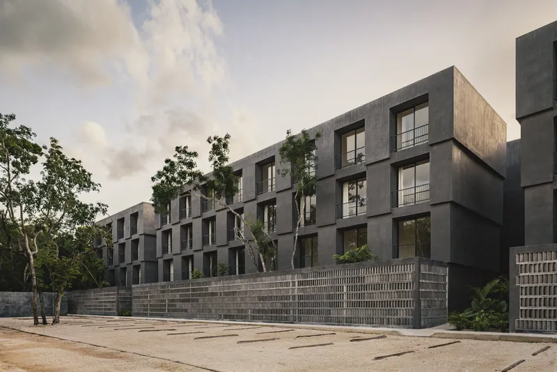 Angled view of the staggered concrete block facade with trees emerging between residential units