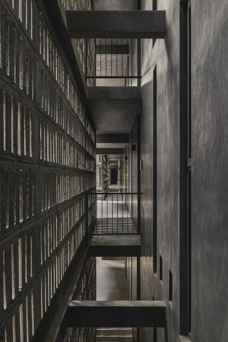 Vertical view through the stairwell showing alternating concrete bridges and perforated brick screen walls