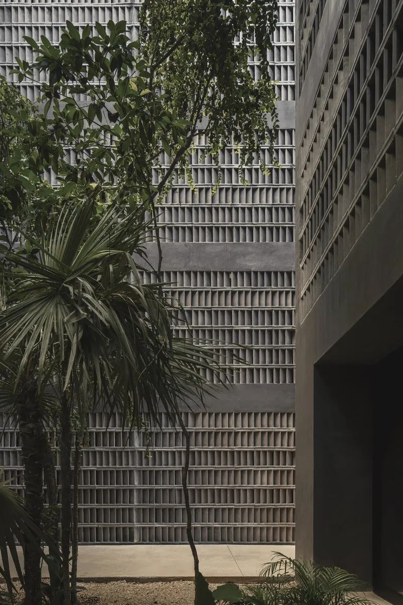 Courtyard view of the gridded concrete screen wall with palms and tropical plantings