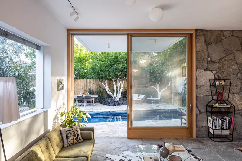 Timber sliding glass doors opening to pool terrace with stone feature wall and exposed ceiling pendant