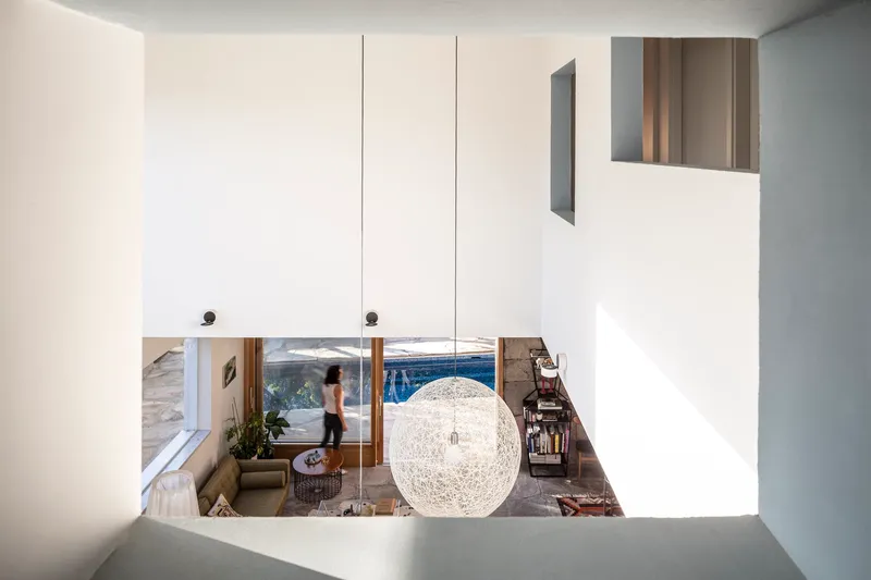 View down from upper level through void showing spherical pendant light and figure in living space below