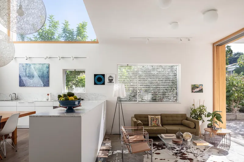 Kitchen island and living space with wire pendant lights and horizontal louvered window