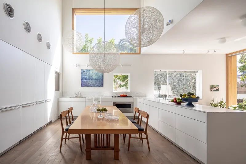 White kitchen with spherical pendant lights suspended below a high clerestory window