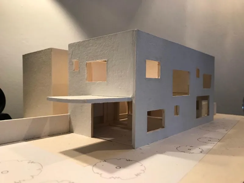 Physical model of a two-story volume with punched window openings in textured gray material
