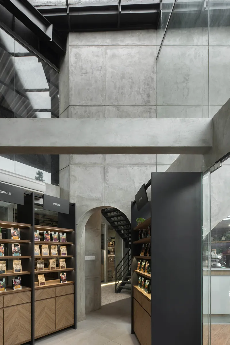 Interior view of concrete beams and arch framing the retail shelving and steel staircase
