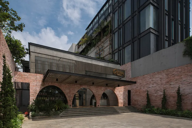 Courtyard view of the arched brick facade and canopy with planted beds flanking the steps