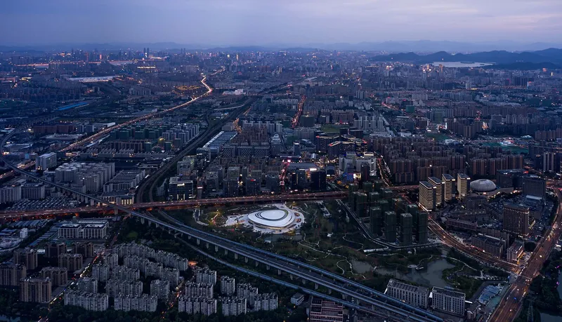 Wide aerial view showing the domed structure within the dense urban grid at blue hour