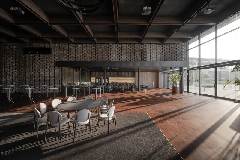 Dining area with exposed timber ceiling beams and floor-to-ceiling windows casting afternoon shadows across hardwood flooring