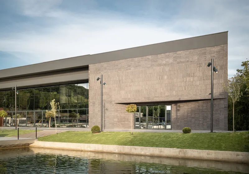 Horizontal brick facade with cantilevered volume and glass terrace overlooking a reflecting pool