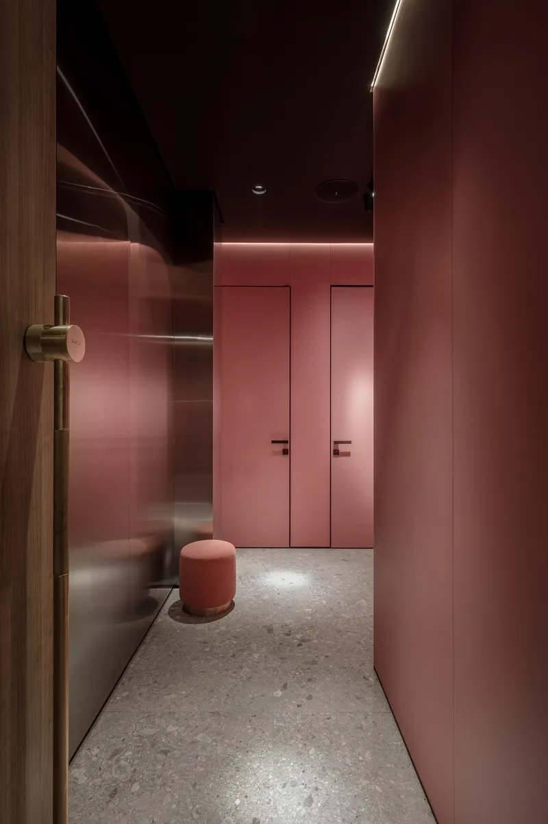 Narrow corridor with pink wall panels and concealed LED lighting at the ceiling line