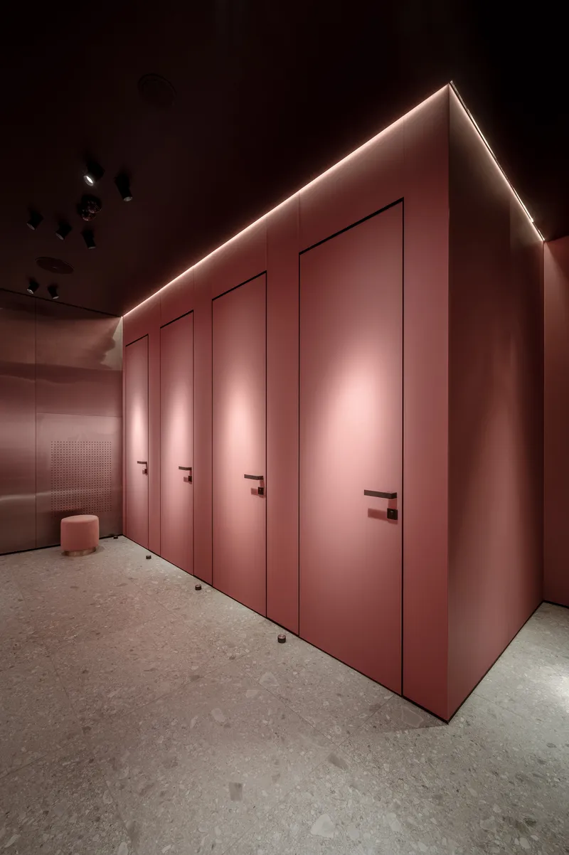 Row of four pink flush doors with concealed LED perimeter lighting and terrazzo flooring