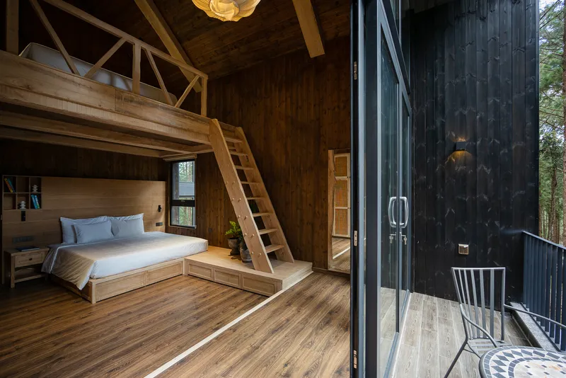 Bedroom with timber loft and open glass doors leading to a corrugated metal-clad balcony