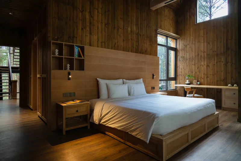 Bedroom with vertical timber wall cladding and integrated headboard shelving above a built-in bed platform